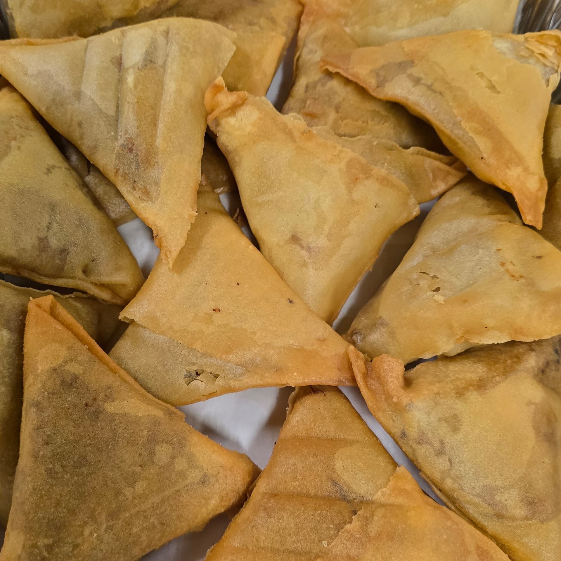 Plate of golden Bangladeshi samosas and pakoras with green chutney