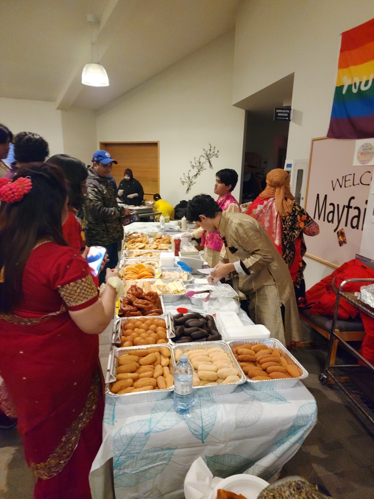 Guests choosing from a colourful spread of Bangladeshi sweets